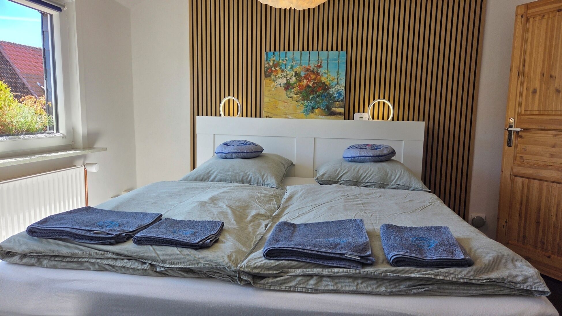 A bed with a headboard, pillows, and folded towels.