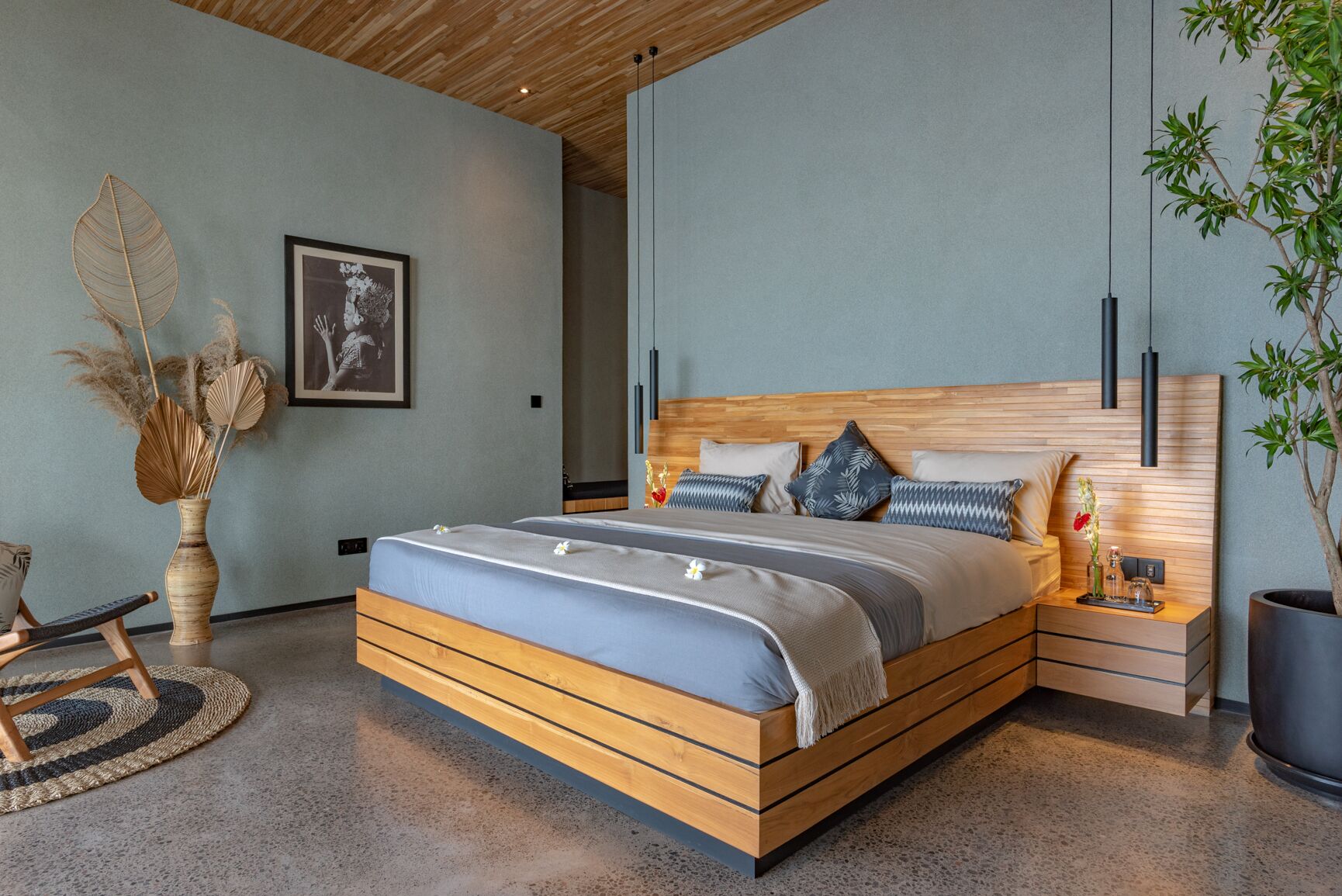 Un dormitorio moderno con una cama de madera, una mesita de noche, una planta grande en maceta y una obra de arte enmarcada en la pared.
