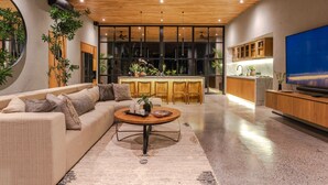 Un salon moderne avec un canapé, une table basse et un téléviseur. Il y a également un coin cuisine avec des meubles en bois et une grande fenêtre.