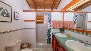 A bathroom with two sinks, a shower, and a toilet.