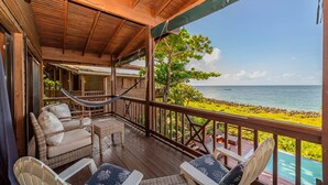 A wooden deck with wicker furniture overlooking a beach and ocean.