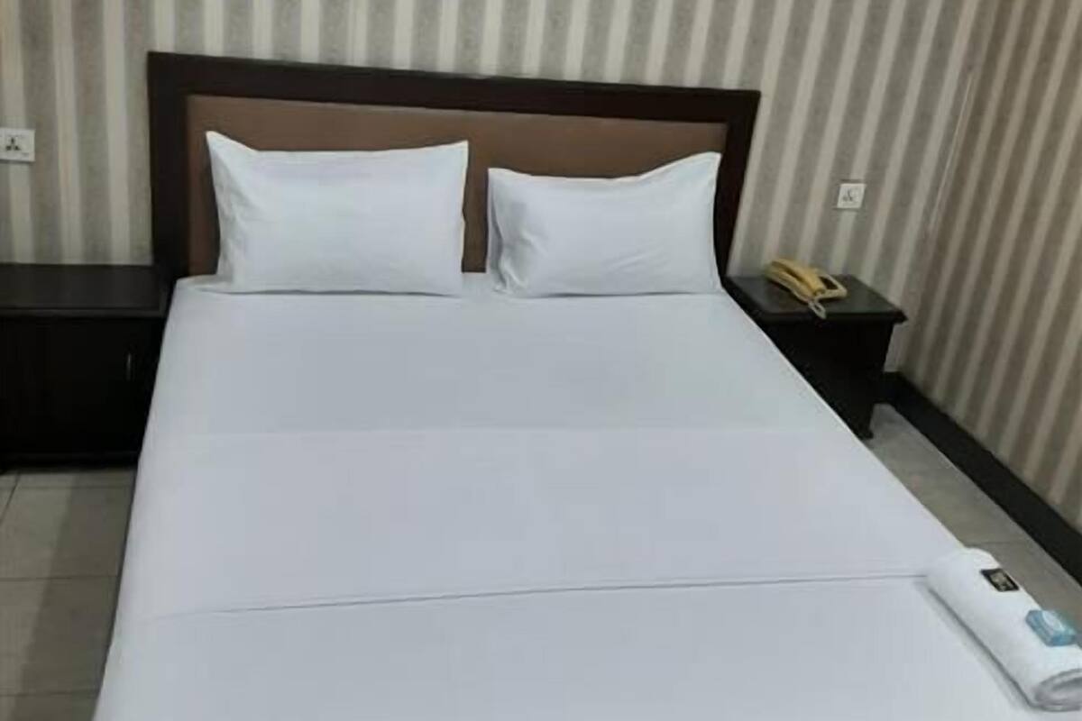 Ein ordentlich bezogenes Bett mit weißen Leinen in einem Hotelzimmer mit Streifenmuster.