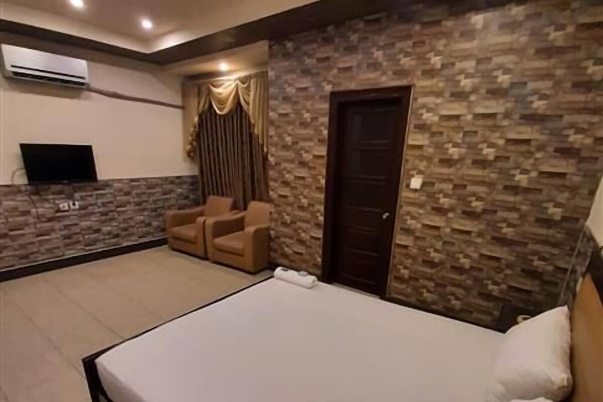 Ein geräumiges Schlafzimmer mit einem großen Bett, einer Sitzecke mit Stühlen, einem Fernseher und einer Steinwand.