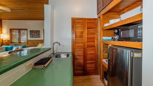 Una cocina compacta con encimera verde, armarios de madera, un refrigerador de acero inoxidable y un microondas.