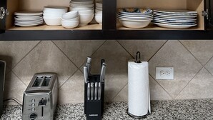 A kitchen with a wooden cabinet containing plates, bowls, and a knife block. - Single home  with 5 bedrooms  sleep 10 at  a corner lot, fully garage to use (Pflugerville)