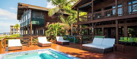 A wooden building with a pool, lounge chairs, and a view of the ocean.