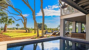 A swimming pool with lounge chairs and a view of a landscaped garden and distant trees. - Live Your Best Oceanfront Life!  Exquisite Ocean Views, Private Pool, Expansive Outdoor Areas & More (Isle of Palms)