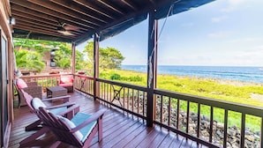 A wooden deck with outdoor furniture, a view of the ocean, and a rocky shoreline. - Oak Ridge Suite - Ground Level Double (West End)