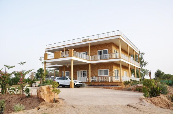 A multi-story building with balconies, a driveway, and surrounding landscaping.