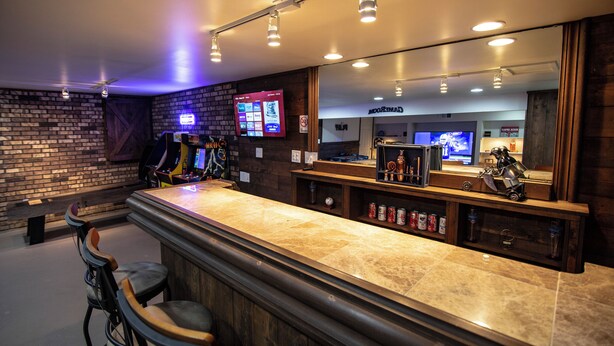 Un espace bar doté d’un comptoir en marbre, de chaises en bois et d’un mur en briques.