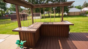 Une terrasse en bois avec une pergola et un jardinier.