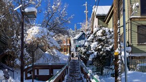 Una escalera cubierta de nieve que lleva a un edificio con tejado verde y puerta azul.