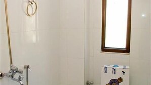A small, clean bathroom with white tiles, a toilet, a shower, and a window. - Skardu Royal Hotel and Restaurant (Skardu)
