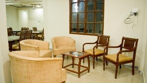 A room with a dining table, four chairs, a glass-top coffee table, and a large window. - Skardu Royal Hotel and Restaurant (Skardu)