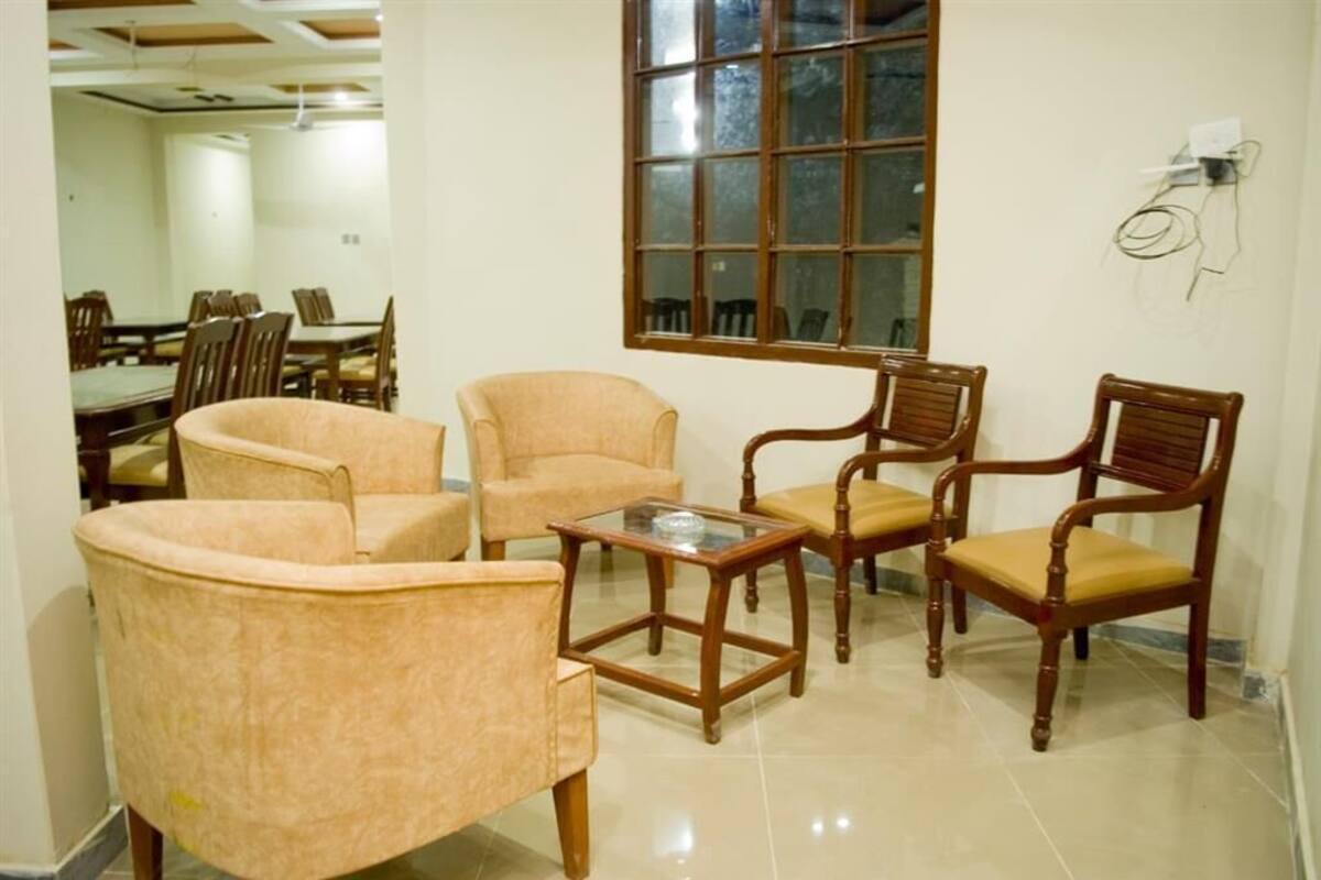 Une pièce comprenant une table à manger, quatre chaises, une table basse avec un plateau en verre et une grande fenêtre.