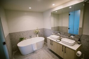 A modern bathroom with a freestanding bathtub, two sinks, and a large mirror. - 5 star couples hideaway in the country, enjoy privacy and space - w hot tub (Penrose)