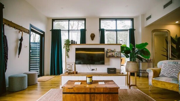 A living room with a wooden coffee table, a flat-screen TV, and a sofa. - 5 star couples hideaway in the country, enjoy privacy and space - w hot tub (Penrose)