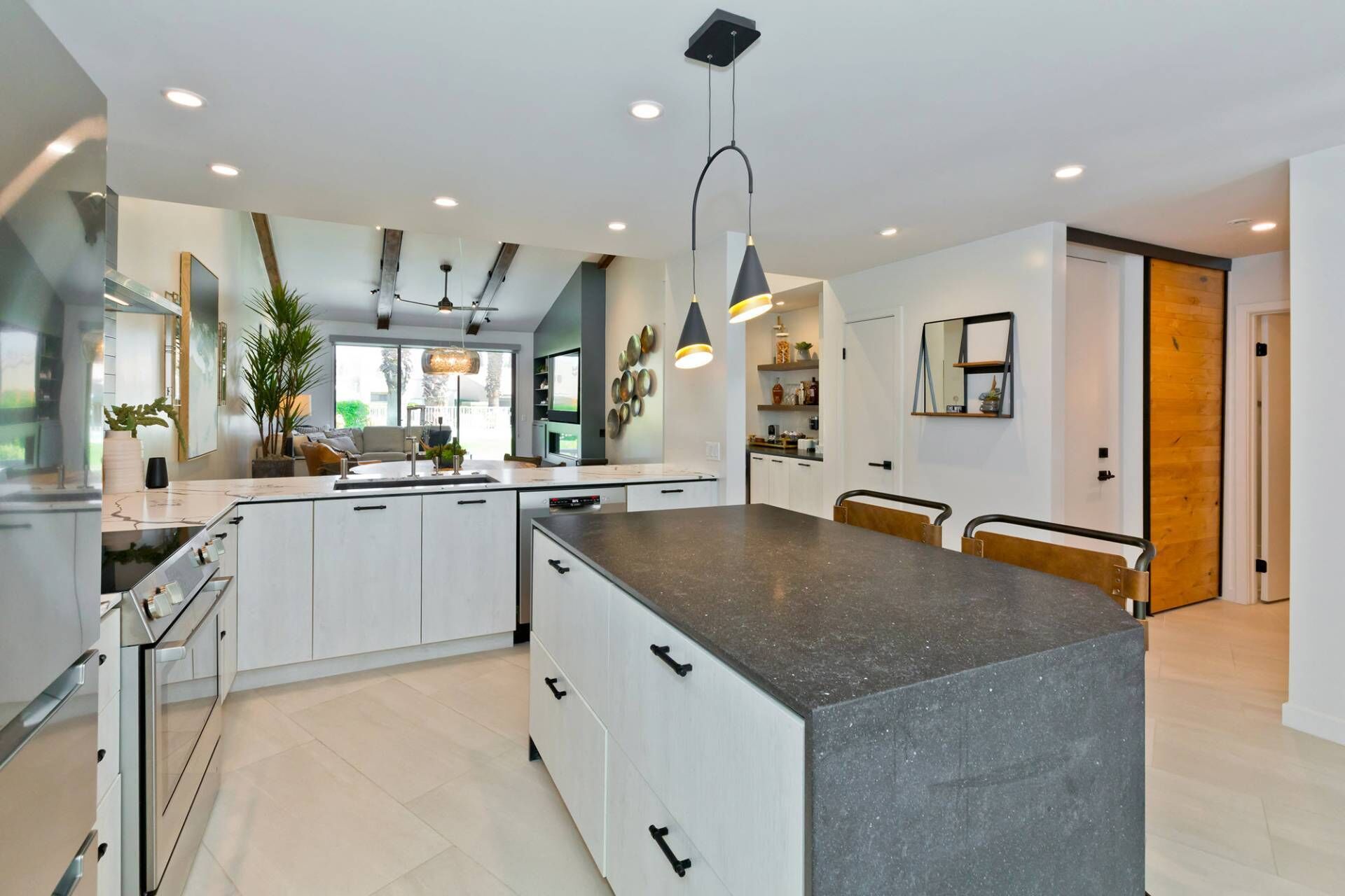 A modern kitchen with white cabinets, a granite countertop, and pendant lighting.
