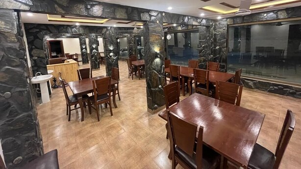 A restaurant with stone walls, wooden tables, and chairs. - Eden Rock Skardu (Skardu)