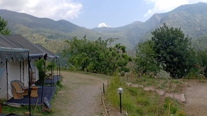 A rustic cabin with a porch, surrounded by a mountainous landscape. - Hidden Valley Camp (Nainital)