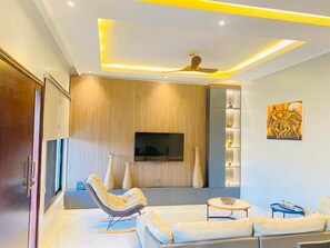 A modern living room with a sofa, chairs, a TV, and decorative vases.
