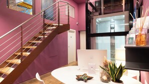 A modern office space with a spiral staircase, a white desk with a computer, a potted plant, and a decorative starfish. - Gogò Petit Hotel (Florence)