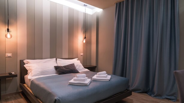 A modern hotel room with a large bed, two bedside tables, and a nightstand. - Gogò Petit Hotel (Florence)