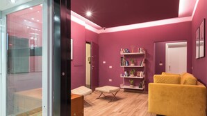A modern living room with a yellow sofa, a wooden floor, and a bookshelf. - Gogò Petit Hotel (Florence)
