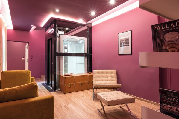 Un interior moderno con una pared morada, un armario de madera, un sillón amarillo, un sillón beige y un cartel de Pilates.