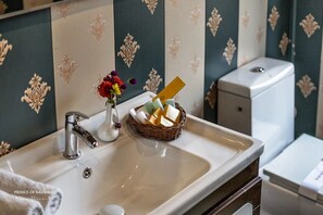 A bathroom with a sink, a basket of toiletries, and a toilet. - Prince of Kashmir Luxury Houseboat  (Srinagar)