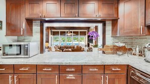 A kitchen with wooden cabinets, a microwave, and a dishwasher. - Direct Oceanfront Kalapaki Beach Home, Wrap-Around Lanai, A/C, Views, Sleeps 8 (Lihue)