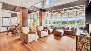 A spacious living area with multiple seating options, large windows offering a view of the outdoors, and a modern design with exposed beams. - Direct Oceanfront Kalapaki Beach Home, Wrap-Around Lanai, A/C, Views, Sleeps 8 (Lihue)