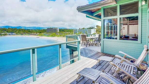 A beachfront property with a deck, chairs, and a view of the ocean and beach. - Direct Oceanfront Kalapaki Beach Home, Wrap-Around Lanai, A/C, Views, Sleeps 8 (Lihue)