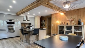 A modern kitchen with stainless steel appliances, a central island with bar stools, and wooden accents.