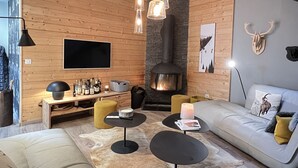 Un salon moderne avec une cheminée, des murs en bois, un canapé, une table basse et un téléviseur fixé au mur.