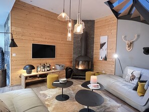 A modern living room with a fireplace, wooden walls, a sofa, a coffee table, and a TV mounted on the wall. - [CheZ BlaisE]  (Cauterets)