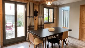 Un coin repas comprenant une table, des chaises, une horloge et des rideaux.
