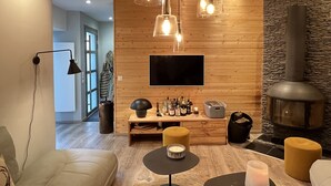 Un salon moderne doté d’une cheminée, de murs recouverts de lambris en bois, d’un téléviseur à écran plat et de différents types de sièges.