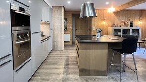 Une cuisine moderne dotée d’appareils électroménagers en acier inoxydable, d’un plafond en bois et d’un îlot central agrémenté de tabourets de bar.