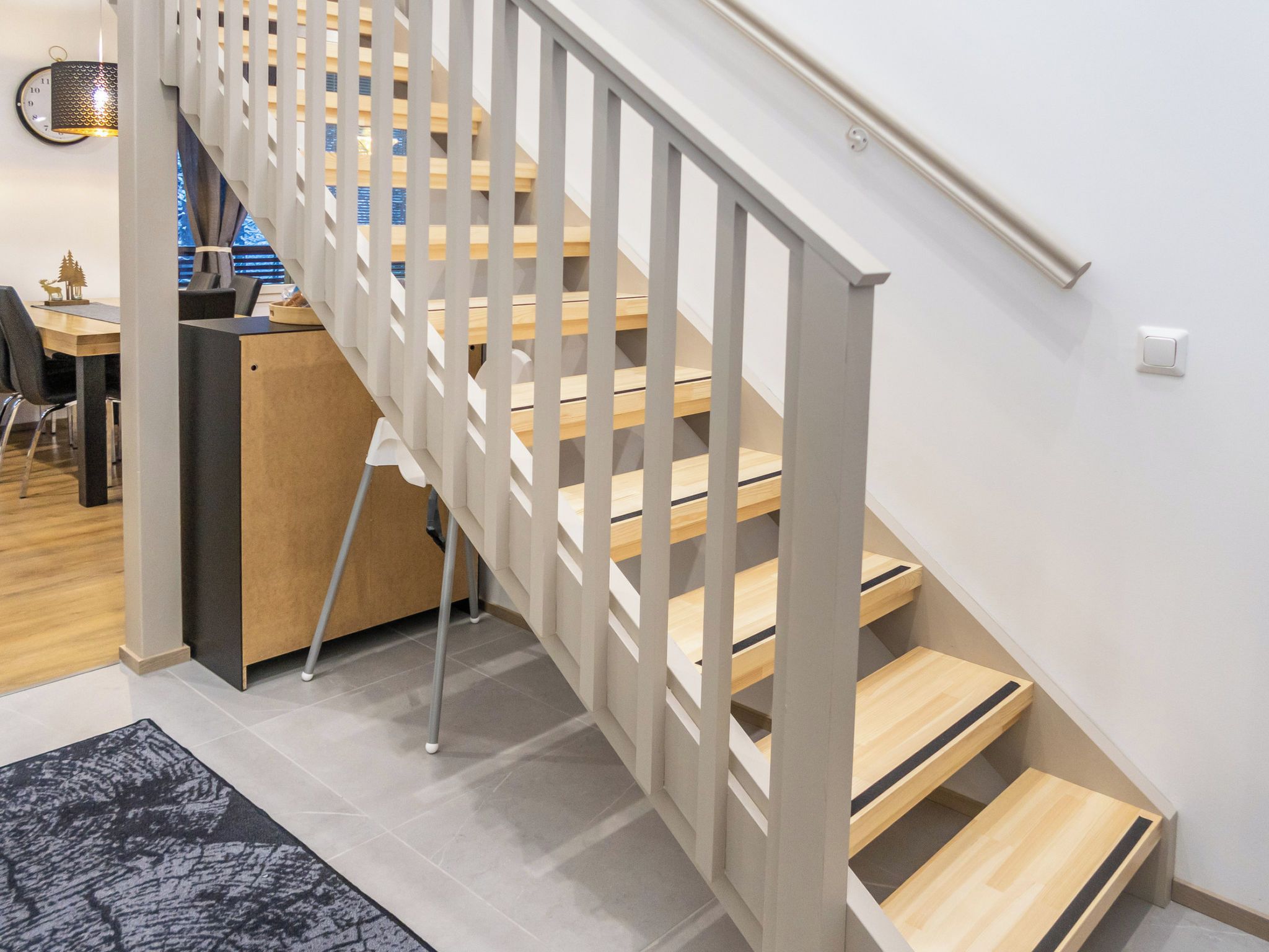 Un escalier moderne avec des marches en bois et des rampes blanches, menant à l’étage supérieur.
