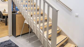Un escalier moderne avec des marches en bois et des rampes blanches, menant à l’étage supérieur.
