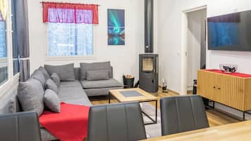 Un salon moderne avec un canapé d’angle, une table basse en bois, un téléviseur et une cheminée.