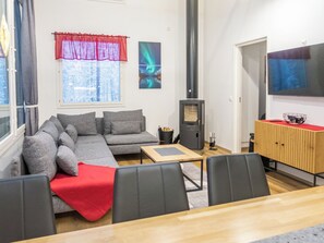 Una sala moderna con un sofá modular, una mesa de centro de madera, un televisor y una chimenea.