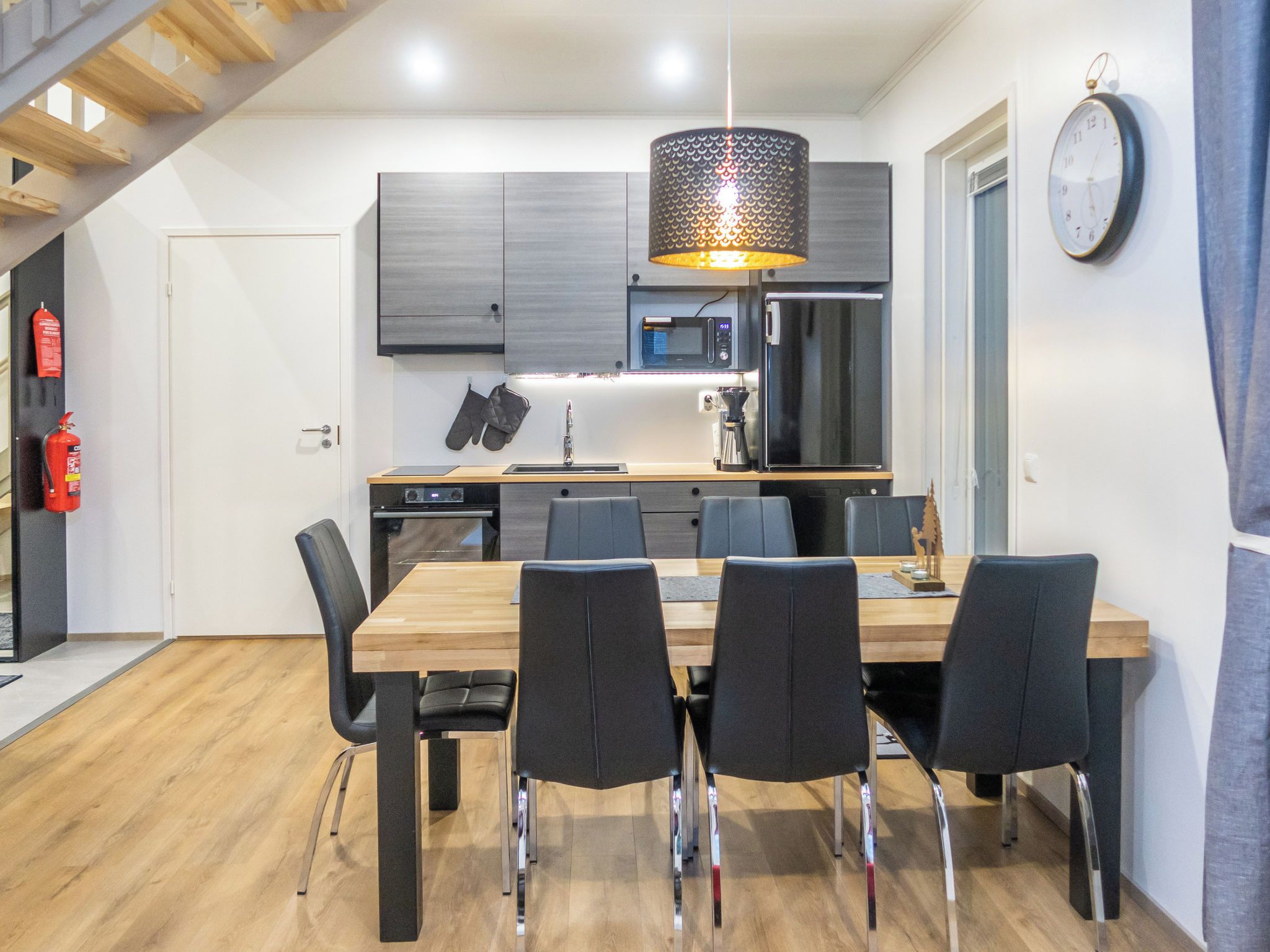 Een moderne keuken met een eethoek, houten vloeren en een klok aan de muur.