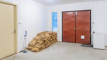 Une pièce contenant une pile de bois de chauffage, un balai, une porte et un réfrigérateur.