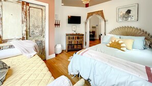 Ein Schlafzimmer mit zwei Betten, einem Fernseher, einem Bücherregal und einem großen Fenster.