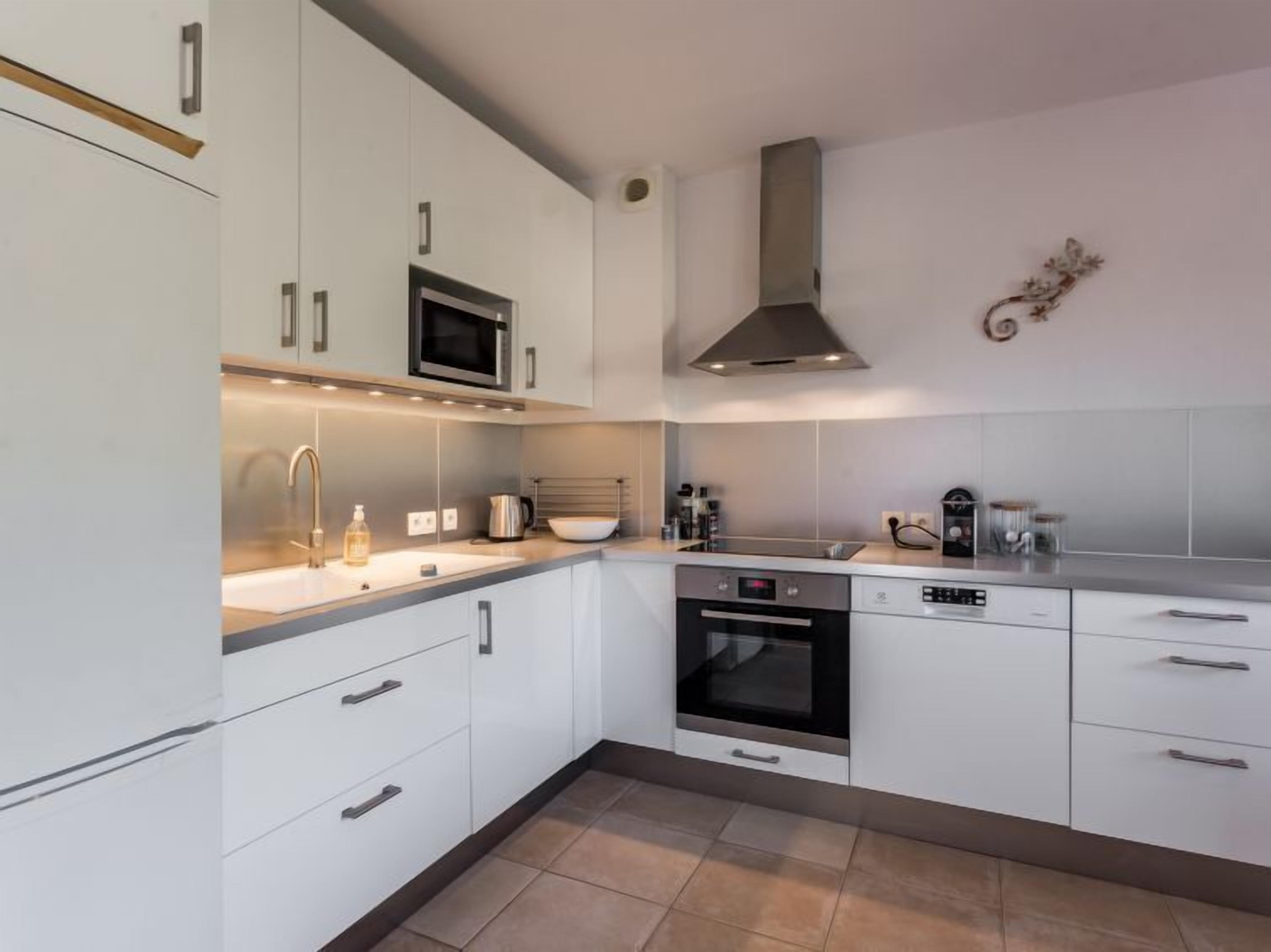 A modern kitchen with white cabinets, stainless steel appliances, and a built-in oven.
