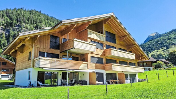 A multi-story wooden chalet with balconies, a covered patio, and a view of a lush green valley. - Greenview by Interhome (Blankenburg)