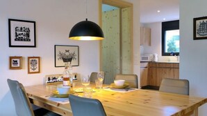 A dining area with a wooden table, chairs, a hanging light fixture, and framed artwork on the walls. - Greenview by Interhome (Blankenburg)