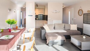 Ein modernes Wohnzimmer mit Essbereich, einer Sofagarnitur und einer Küche im Hintergrund.